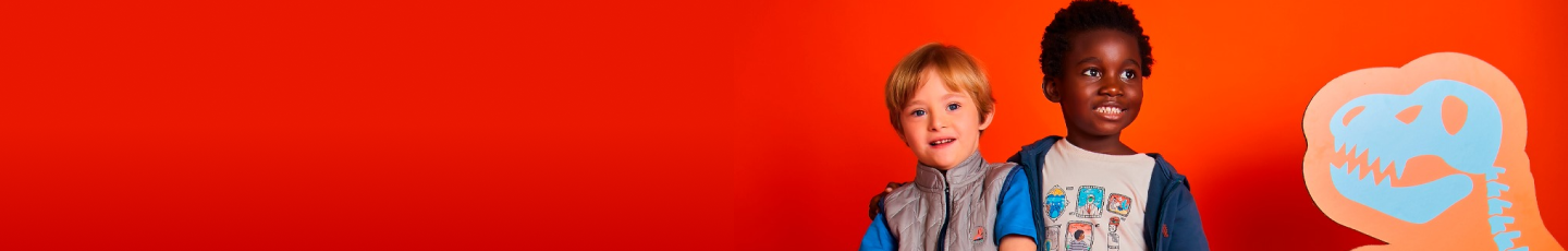 Dois meninos sorridentes em frente a um fundo vermelho e laranja vibrante, com um desenho de dinossauro azul ao lado.
